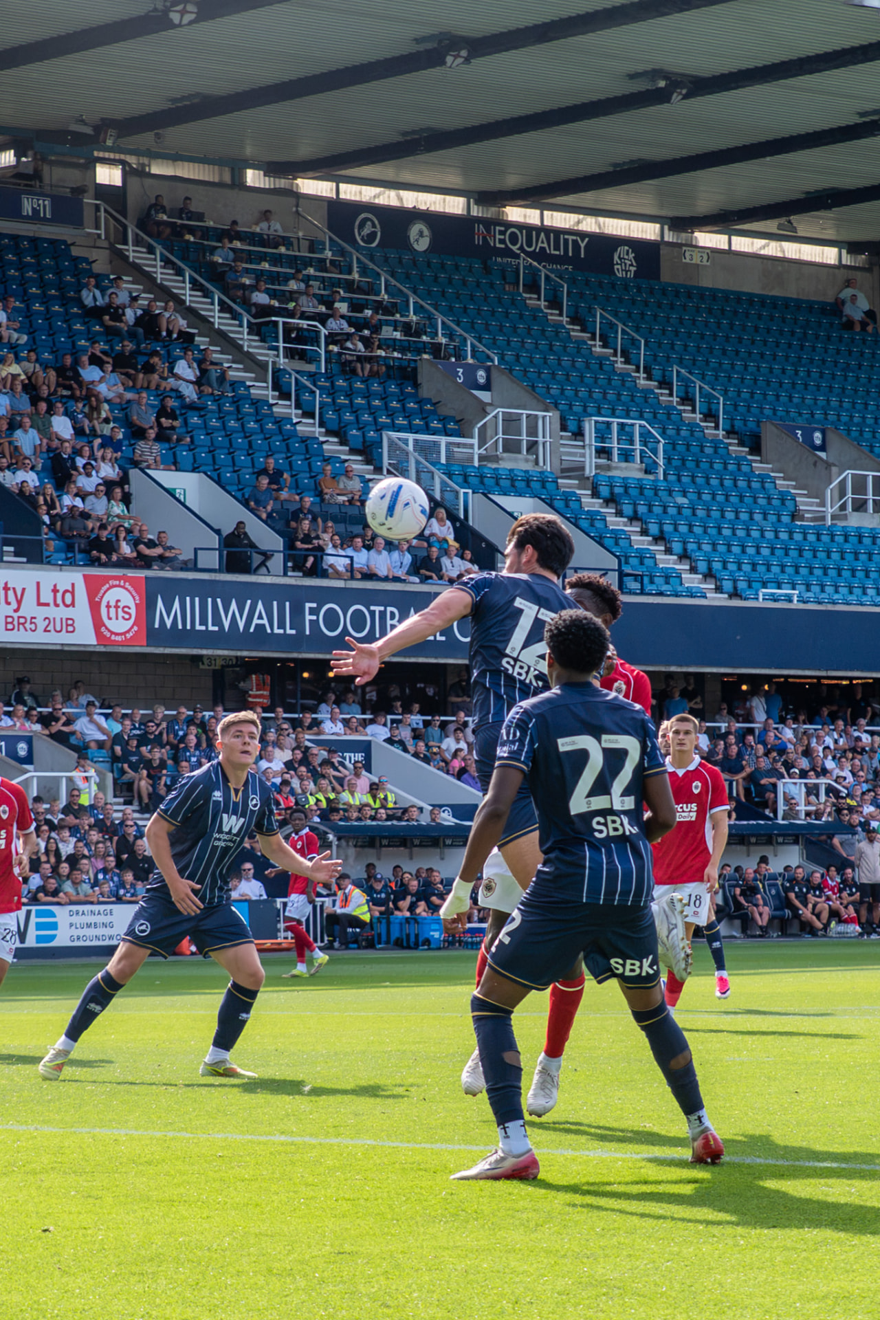 Millwall player rising to meet a header in front of the main stand