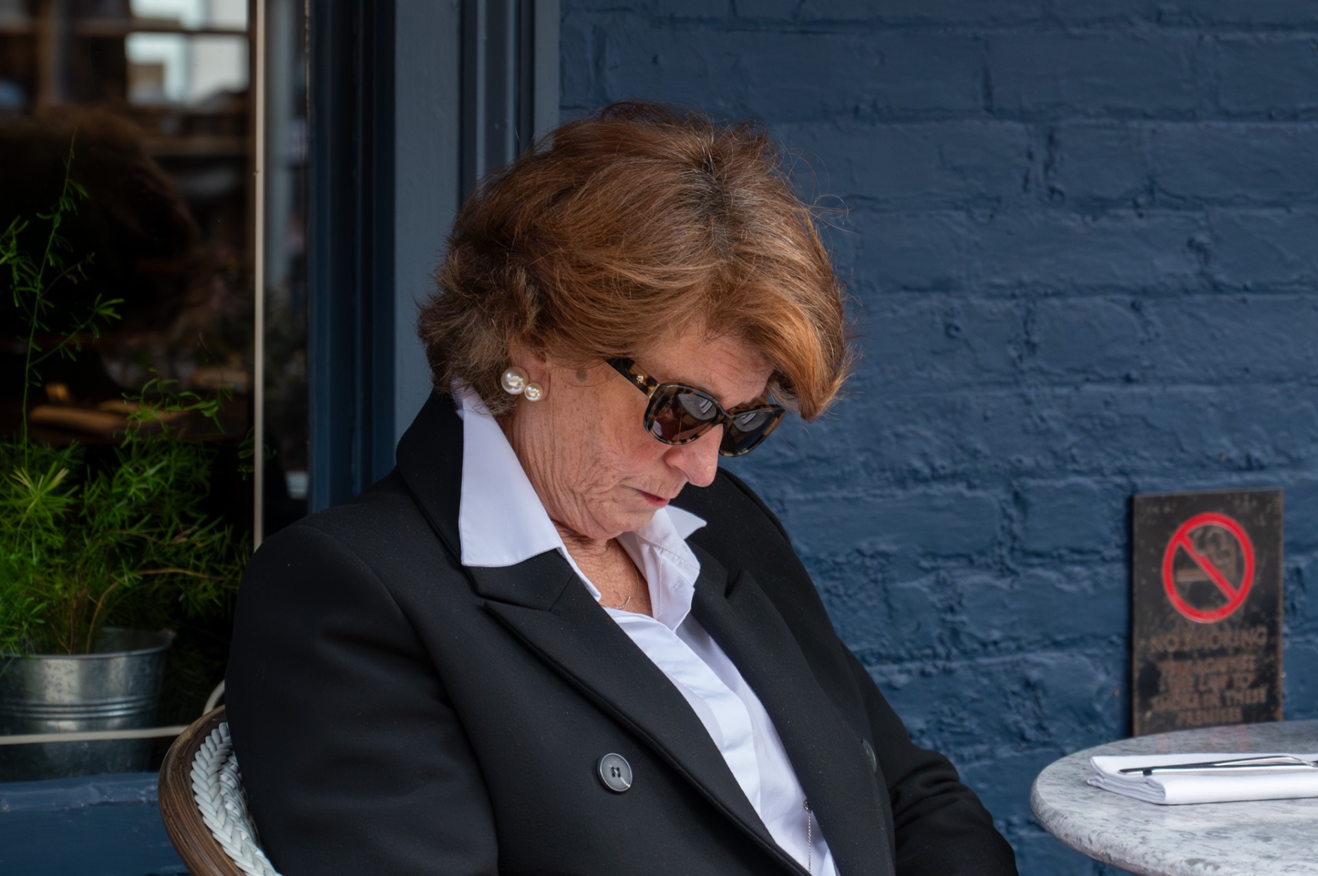 Portrait of a woman in sunglasses outside a café