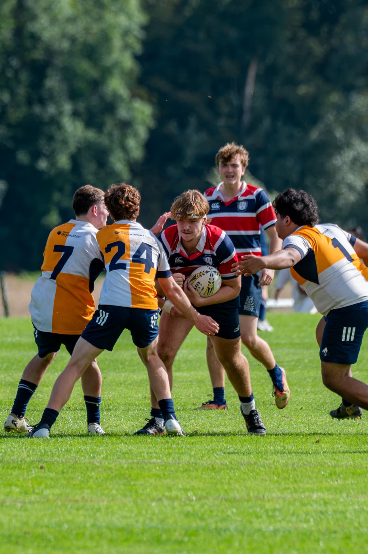 Rugby ball carrier facing three defenders