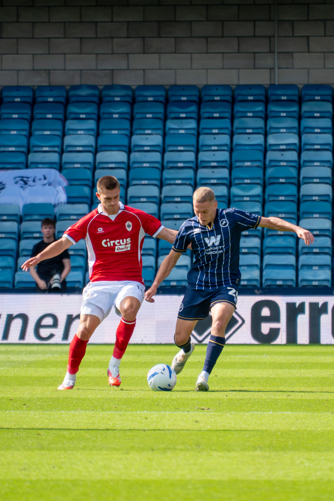 Millwall defender shielding the ball from a red-shirted opponent