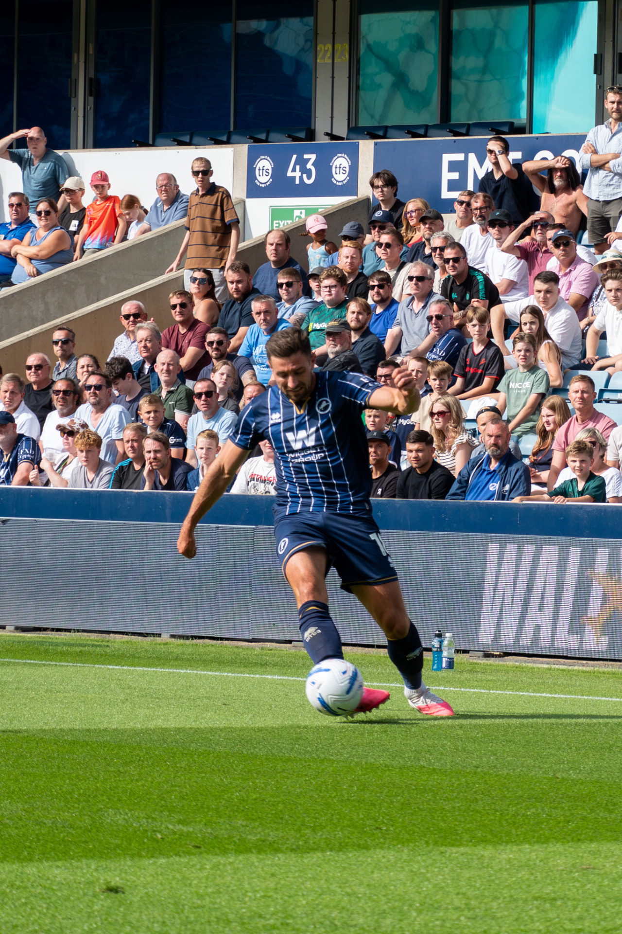 Millwall player crossing the ball in front of a packed stand