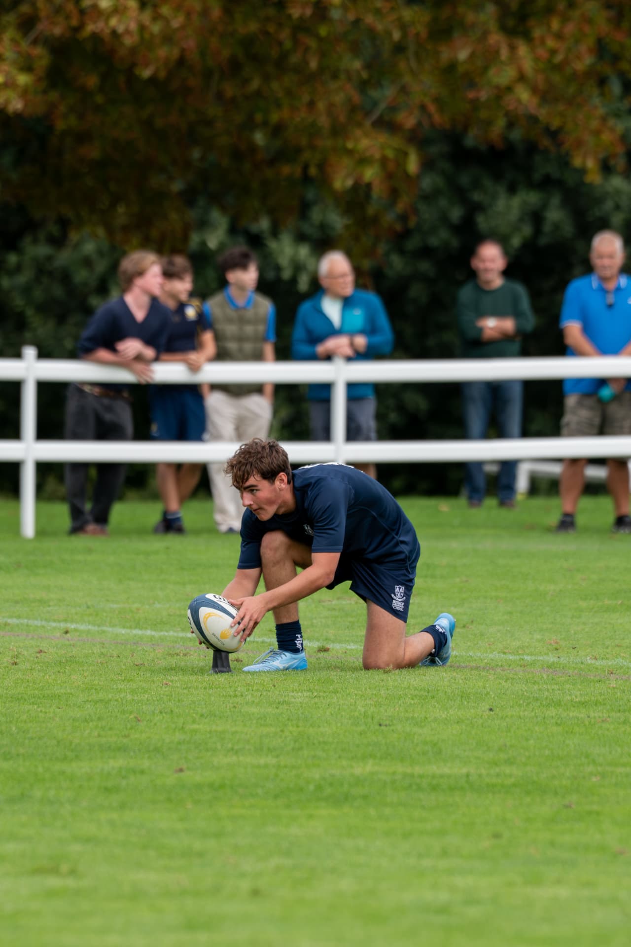 Rugby player kneeling to tee the ball for a conversion kick