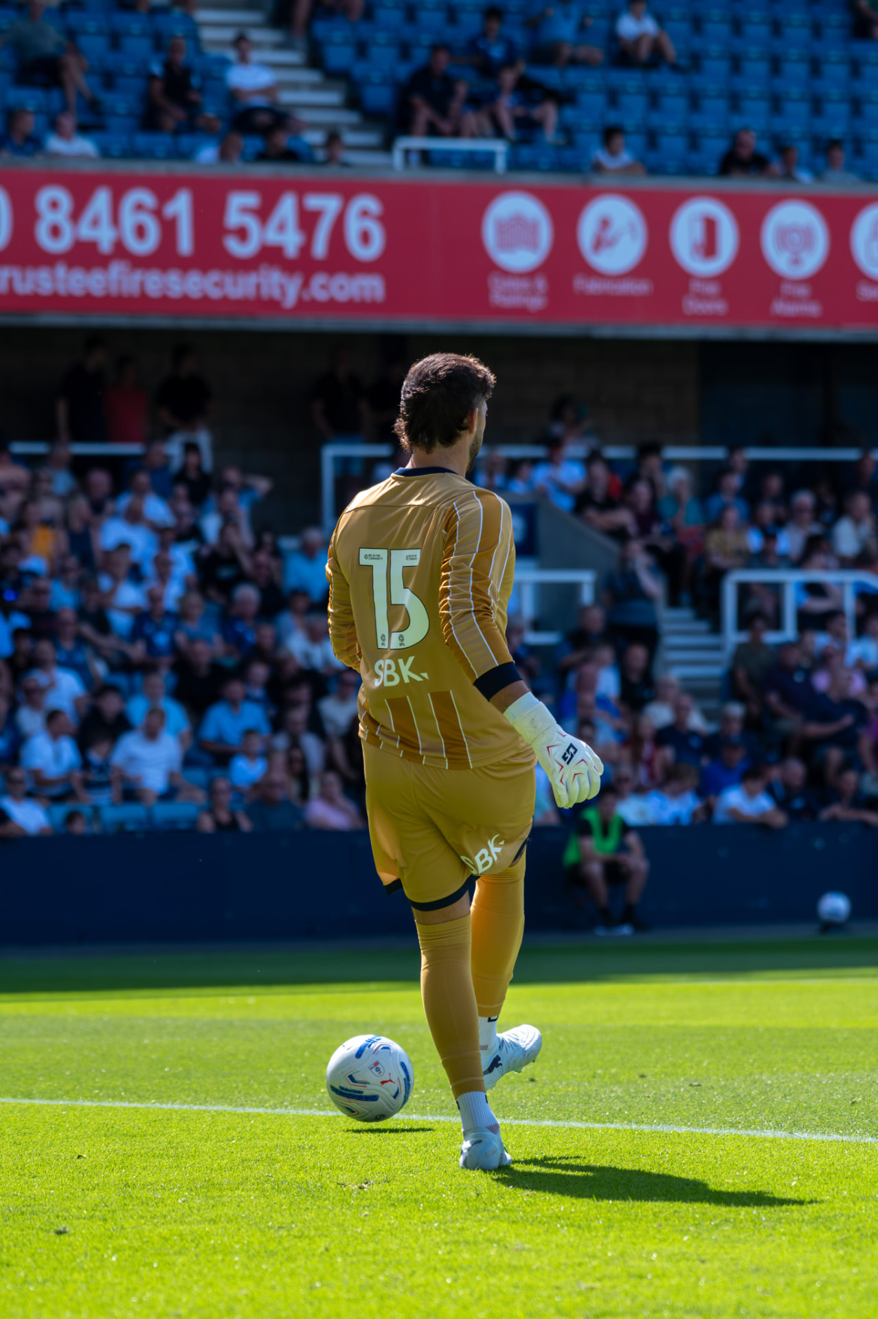 Goalkeeper stepping onto the ball in front of the stands