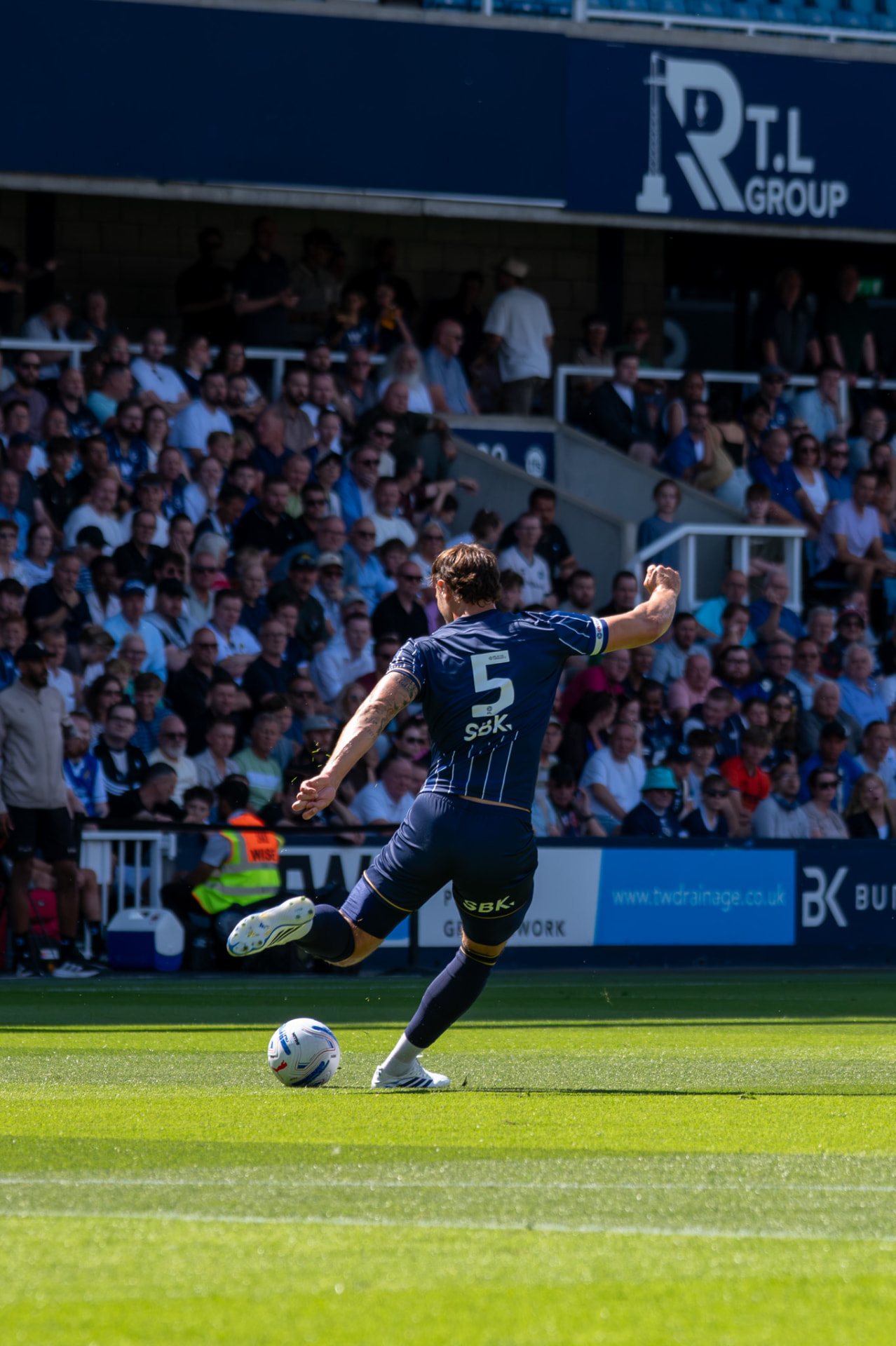 Player swinging a long pass across the pitch