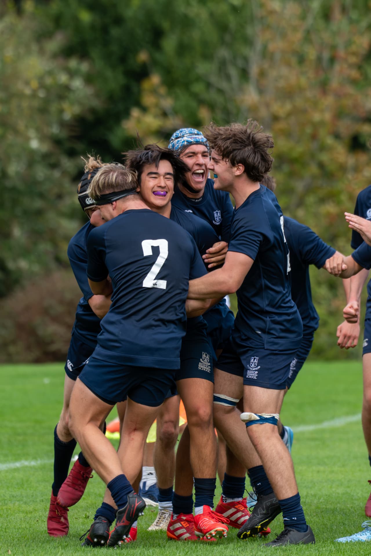 Rugby team celebrating together in a huddle on the pitch