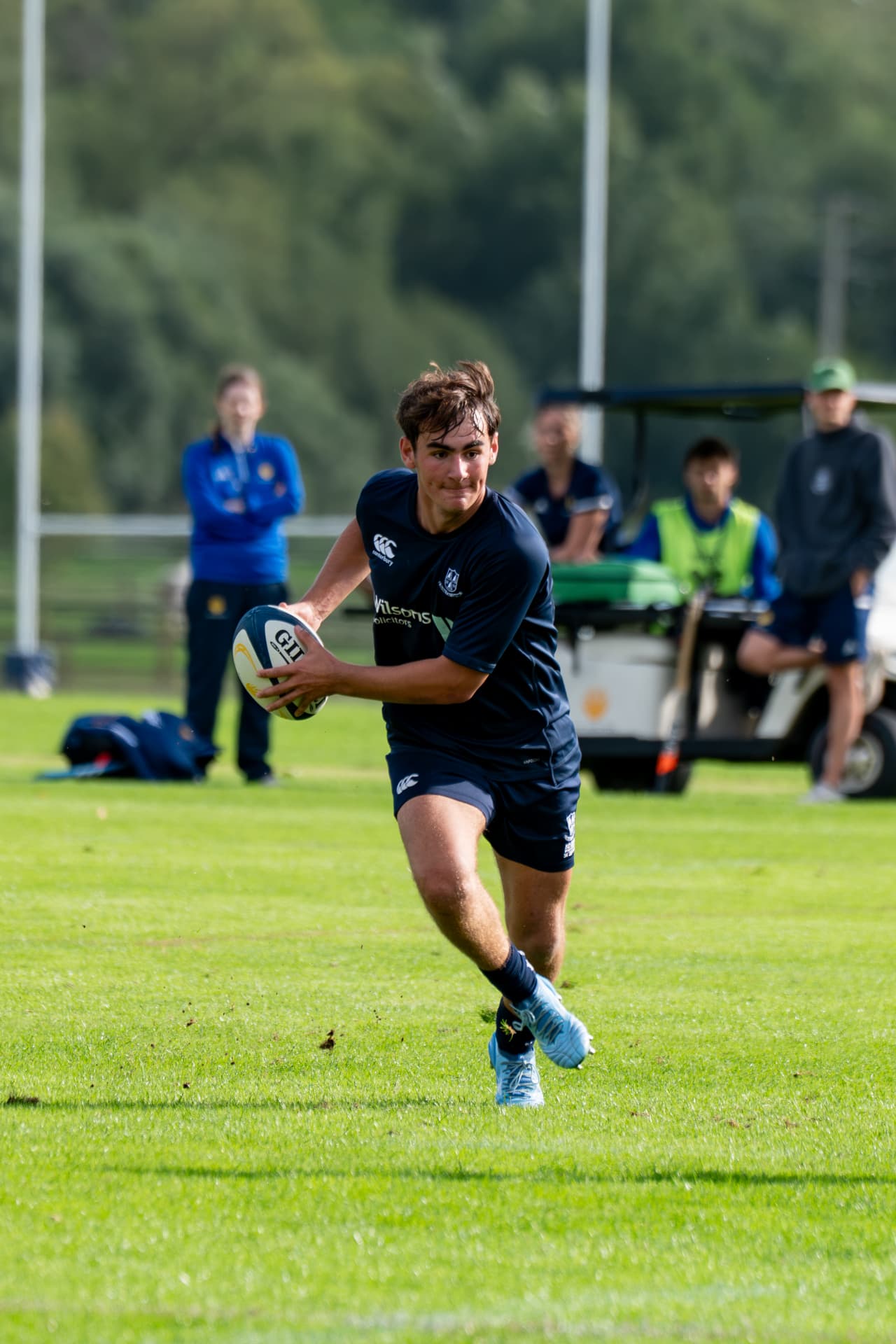 Rugby player carrying the ball into open grass