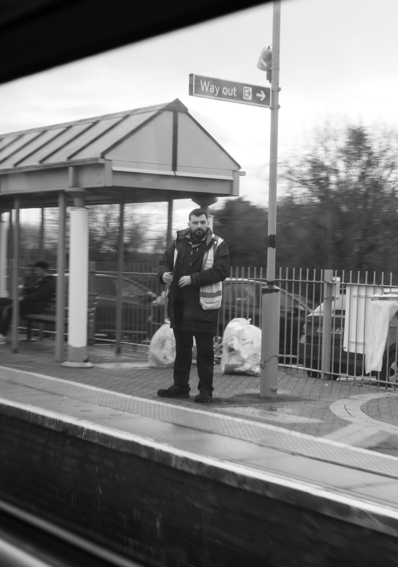 Station guard standing on a platform, seen from a train window