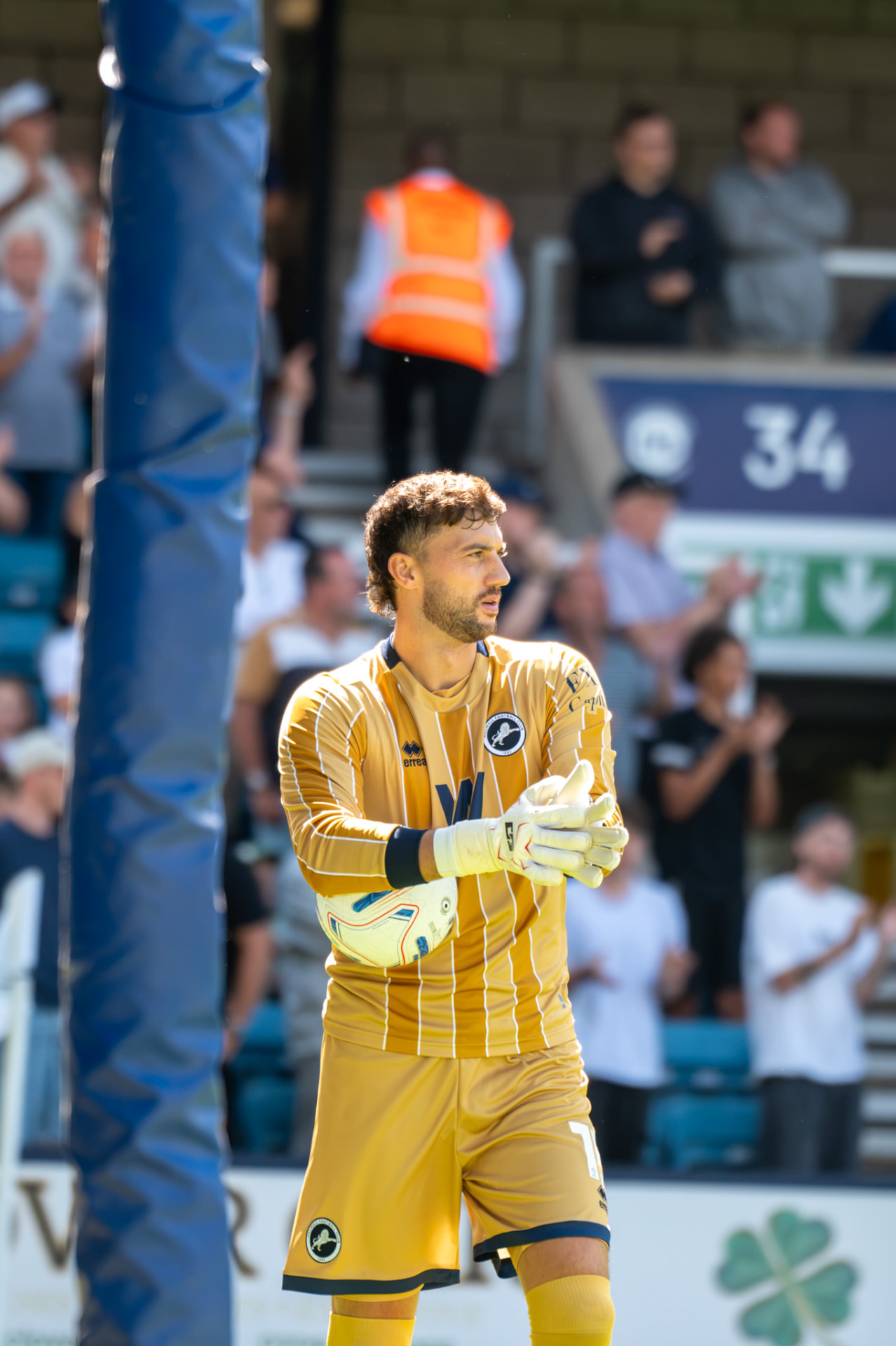 Goalkeeper in gold kit applauding the crowd